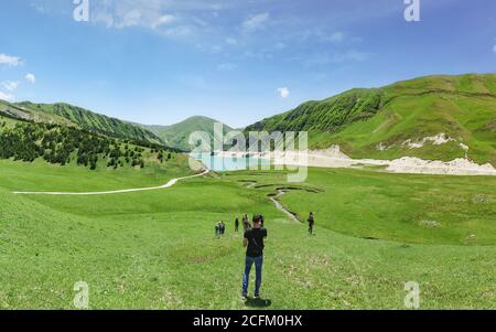 Botlikh Bezirk, Dagestan, Russland - 01. Juni 2019: Touristen steigen zum See kezenoi am an der Stelle des Zusammenflusses des Flusses Harcum. Üppiger g Stockfoto