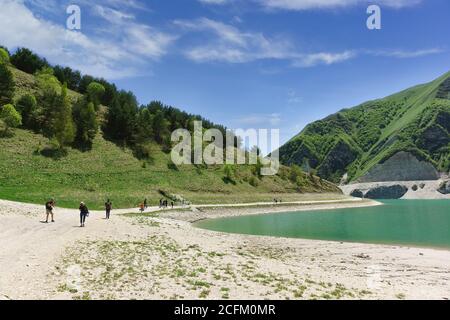 Botlikh Bezirk, Dagestan, Russland - 01. Juni 2019: Touristen mit Kameras sind am Ufer des Sees Kezenoi am. Grünes Gras auf den Berghängen in e Stockfoto