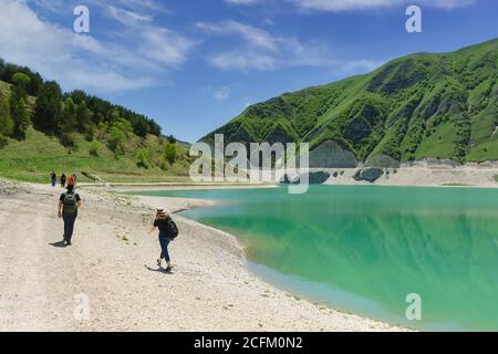 Botlikh Bezirk, Dagestan, Russland - 01. Juni 2019: Touristen gehen am Ufer des Sees Kezenoi am. Grünes Gras auf den Berghängen im frühen Summ Stockfoto