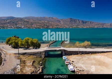 Alte Windmühlen und Kanal auf einem schmalen Damm und Stätte einer antiken minoischen Stadt (Elounda, Kreta, Griechenland) Stockfoto