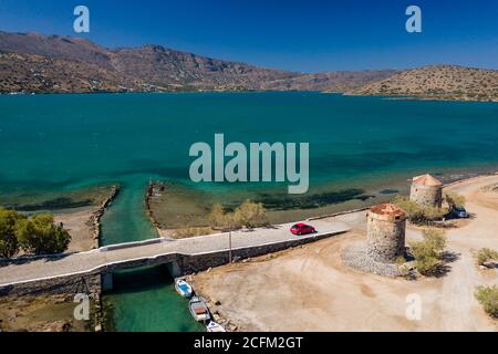 Alte Windmühlen und Kanal auf einem schmalen Damm und Stätte einer antiken minoischen Stadt (Elounda, Kreta, Griechenland) Stockfoto