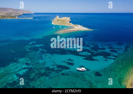 Luftaufnahme einer kleinen Insel und Boote in einem kristallklaren blauen Ozean (Kolokitha, Elounda, Kreta, Griechenland) Stockfoto