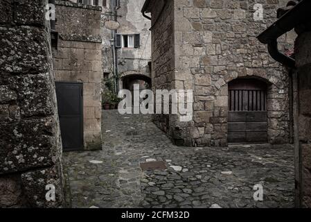 Gasse der mittelalterlichen alten Tuff City Sorano mit grünen Pflanzen und Kopfsteinpflaster, Reisen Italien Hintergrund Stockfoto