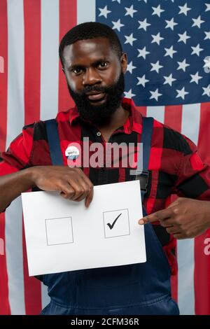 Zeitgenössische junge afroamerikanische Reparaturman zeigt auf Zecke in einer der Quadrate Stockfoto