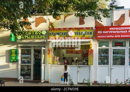 Jewpatoria, Krim, Russland-12. September 2019: Souvenirläden und Fast-Food-Läden auf der Straße des Kurortes. Melden Sie sich in Russisch 'Krim-Chebureks Stockfoto