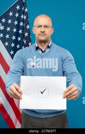 Reife kahle Geschäftsmann in Brillen und blauen Pullover zeigt seine Stimmzettel Stockfoto