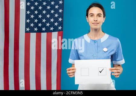 Junge Brünette Zimmermädchen in blauer Uniform zeigt Ihnen ihre Wahl Papier Stockfoto