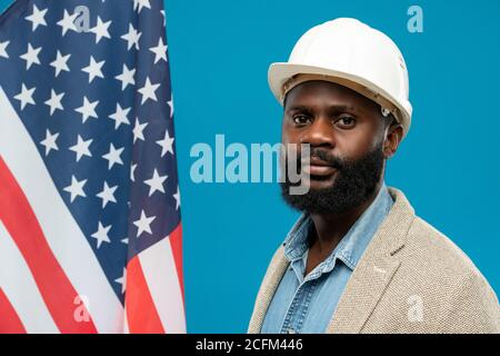 Junger bärtiger afroamerikanischer Ingenieur in Schutzhelm und formalwear Stockfoto