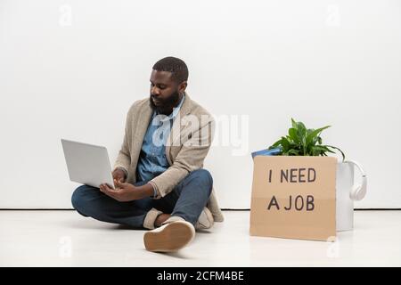 Junger arbeitsloser afrikanischer Mann mit Laptop, um neue zu suchen offene stellen im Netz Stockfoto