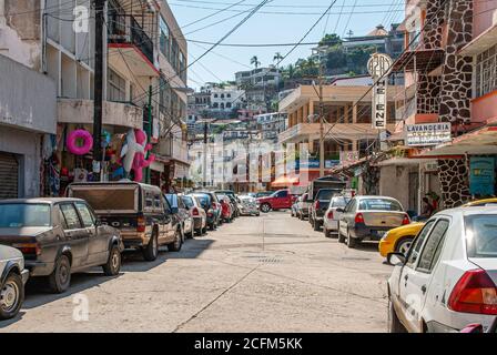 Acapulco, Mexiko - 25. November 2008: Alte Innenstadt. Gemischte Geschäfts-und Wohnstraße mit geparkten Autos, Spielzeug, ein Lavanderia, Waschsalon, und Hügel o Stockfoto