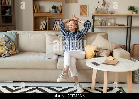 Moderne, entspannte, reife Frau in weißen Jeans, Sneakers und kariertem Hemd Stockfoto