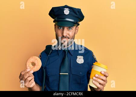 Gutaussehende hispanische Polizei Mann essen Donut und trinken Kaffee skeptisch und nervös, runzelte wegen des Problems. Negative Person. Stockfoto