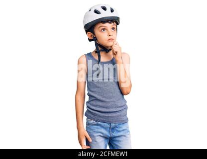 Kleine niedliche Junge Kind trägt Fahrradhelm ernstes Gesicht Denken über Frage mit der Hand auf dem Kinn, nachdenklich über verwirrende Idee Stockfoto