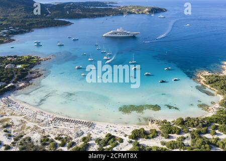 Blick von oben, atemberaubende Luftaufnahme des Grande Pevero Strandes mit Booten und Luxusyachten, die auf einem türkisfarbenen, klaren Wasser segeln. Sardinien, Italien. Stockfoto