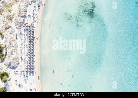 Blick von oben, atemberaubende Luftaufnahme des Strandes Grande Pevero mit Sonnenschirmen und Menschen, die in einem türkisfarbenen, klaren Wasser schwimmen. Sardinien, Italien Stockfoto