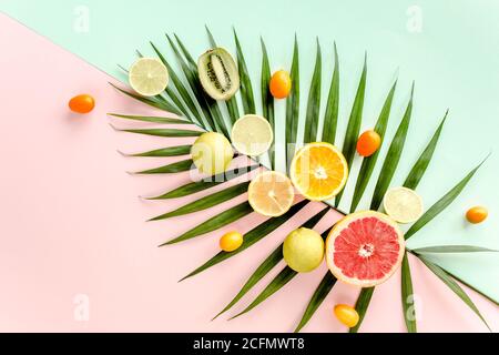 Tropisches Layout aus grünen Palmblättern und Früchten auf buntem Hintergrund. Food-Konzept. Flat Lay, Draufsicht Stockfoto