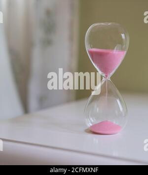 Sandglas auf weißem Tisch. Nahaufnahme. Messen von Zeitvergehen, Countdown oder Tagesroutinekonzept. Stockfoto