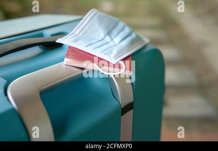 Koffer mit Gesichtsmaske und Reisepass. Reisen nach Übersee während des Covid-19-Pandemiekonzepts. Stockfoto