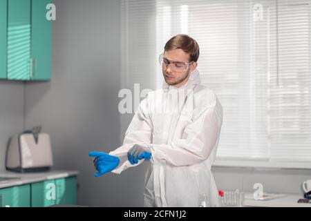 Laborant zieht Handschuhe in einem medizinischen oder wissenschaftlichen Labor an. Stockfoto