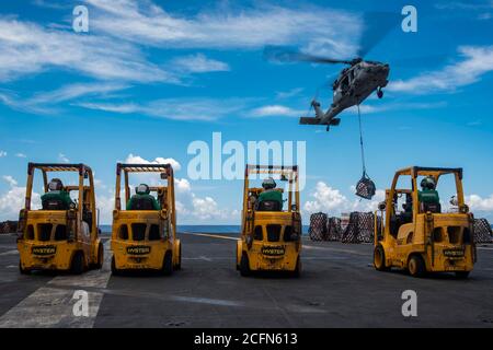 200905-N-ML137-1074 PHILIPPINISCHES MEER (SEPT 5, 2020) ein an die Golden Falcons of Helicopter Sea Combat Squadron (HSC) 12 befestigter MH-60S Sea Hawk transportiert während einer Nachfüllung auf See mit Flottennachschuböler USNS John Ericsson (T-AO 194) Vorräte an das Flugdeck des einzigen vorwärts eingesetzten Flugzeugträgers USS Ronald Reagan (CVN 76). Ronald Reagan, das Flaggschiff der Carrier Strike Group 5, bietet eine kampfbereite Kraft, die die Vereinigten Staaten schützt und verteidigt, sowie die kollektiven maritimen Interessen ihrer Verbündeten und Partner in der Indo-Pazifik-Region. (USA Marineblauer Phot Stockfoto