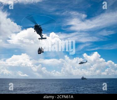 200905-N-ML137-1059 PHILIPPINISCHES MEER (SEPT 5, 2020) ein MH-60S Seahawk, angeschlossen an die Golden Falcons of Helicopter Sea Combat Squadron (HSC) 12, transportiert Fracht während einer Nachschub-auf-See mit Flotte Nachschub Öler USNS John Ericsson (T-AO 194), Und der einzige forward-deployed Flugzeugträger der Marine USS Ronald Reagan (CVN 76), als amphibisches Dock Landungsschiff USS Comstock (LSD 45), rechts, dampft hinter. Ronald Reagan, das Flaggschiff der Carrier Strike Group 5, bietet eine kampfbereite Kraft, die die Vereinigten Staaten schützt und verteidigt, sowie die kollektiven maritimen Interessen ihrer allie Stockfoto