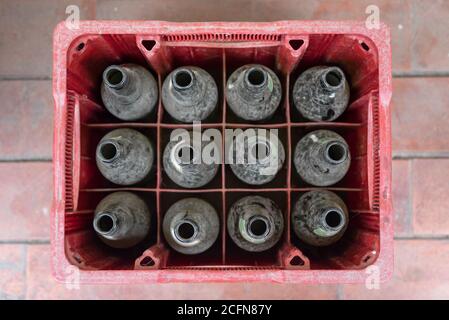 Draufsicht auf eine rote Box voller leerer Bierflaschen. Staubige Flaschen Stockfoto