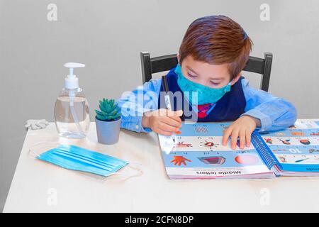 Calgary, Alberta, Kanada. September 2020. Ein freundlicher Garten, Vorschulschüler lernen mit einem Arbeitsbuch mit einer Gesichtsmaske und Handdesinfektionsmittel an Stockfoto