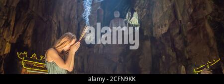 Junge Frau, die in einem buddhistischen Tempel betet, hält Weihrauch Huyen Khong Höhle mit Schreinen, Marmorberge, Vietnam BANNER, LANGFORMAT Stockfoto