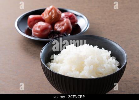 Japanische eingelegte Pflaumen und frisch gekochter Reis gegen eine gesetzt Holzhintergrund Stockfoto