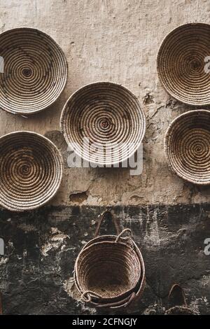 Handgefertigte Weidenkörbe rund hängen an strukturierte Wand in Marrakesch Medina Souk. Traditionelle marokkanische Herstellung. Großer Basar. Stockfoto