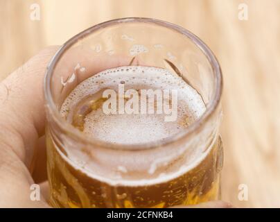 Ein Glas Bier in der Hand eines Mannes aus der Nähe Stockfoto