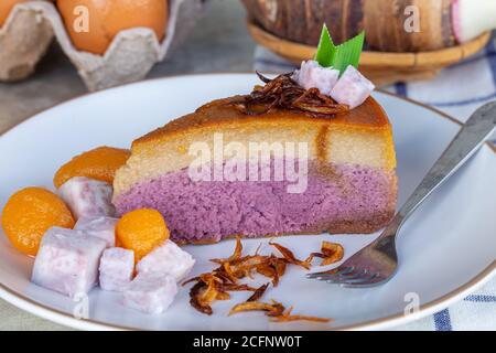 Nahaufnahme von Taro Chiffon Kuchen gekrönt mit Thai Taro Custard und gebratene Zwiebel auf weißem Teller, Konzept von Dessert und Thai Dessert. Stockfoto