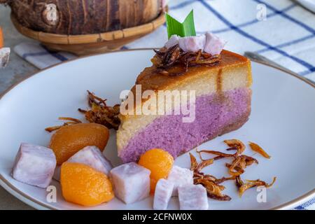 Nahaufnahme von Taro Chiffon Kuchen gekrönt mit Thai Taro Custard und gebratene Zwiebel auf weißem Teller, Konzept von Dessert und Thai Dessert. Stockfoto