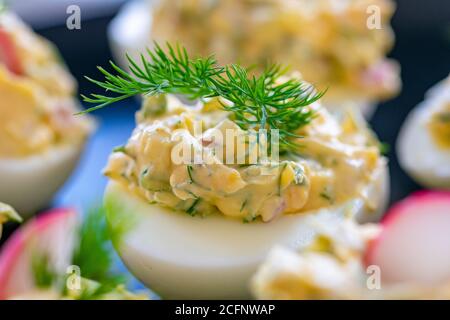 Ein Nahaufnahme Bild von frisch zubereiteten gekochten Eiern gefüllt mit Mayo, Zwiebeln, Ei und Rettich mit Dill garniert. Stockfoto