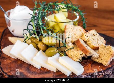 Traditionelle kretische Käseplatte mit Kefalotiri, Tirozouli, Graviera, Anthotyro und Galomizithra Käse mit Kräutern und Oliven (selektiver Fokus) Stockfoto
