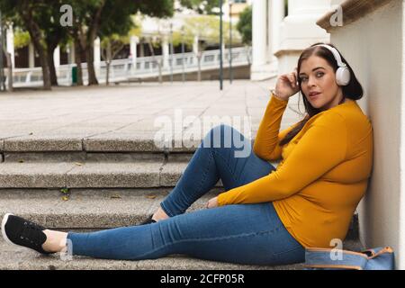 Kurvige kaukasische Frau, die Musik auf ihrem Smartphone hört Stockfoto