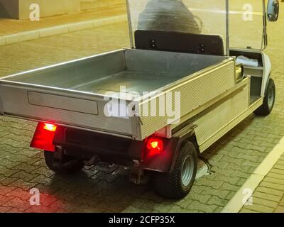 Ein kleines Elektroauto mit Gepäckfach und roten Scheinwerfern auf der Rückseite sitzt auf dem Bürgersteig. Vollbild-Foto Stockfoto