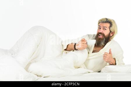 Start Tag mit gutem Kaffee. Gourmet-Espresso. Genießen Sie den morgendlichen Kaffee. Der Körper wurde von wesentlichen Komponenten für eine gute Gesundheit und Energie beraubt. Schöner Mann trinkt Kaffee. Reifer bärtiger Mann im Bett. Stockfoto