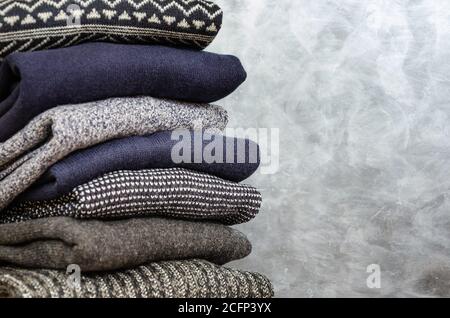 Stapel von gefalteten warmen Strickpullover für Herren auf grauem Hintergrund. Speicherplatz kopieren. Nahaufnahme Stockfoto