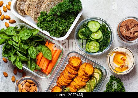 Vorbereitung gesunder Mahlzeiten für die Woche. Vegane Lebensmittel und Snacks in Behältern, grauer Hintergrund. Flaches Lay von Kochpflanzen basierte Lebensmittel. Stockfoto
