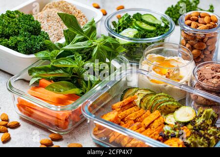 Vorbereitung gesunder Mahlzeiten für die Woche. Vegane Lebensmittel und Snacks in Behältern, grauer Hintergrund. Flach legen Kochen Lebensmittel. Stockfoto