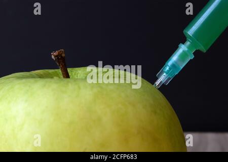 Grüner Apfel auf einem Holzbrett und Spritze darin Extraktion grüne Flüssigkeit Stockfoto