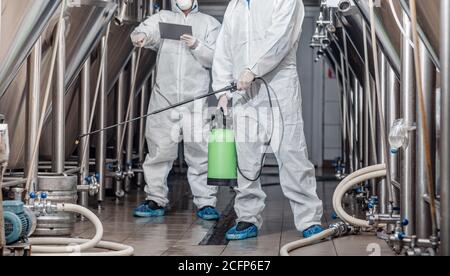 Arbeiter in Schutzanzügen mit Spritzbeutel und Tablet in Werk Stockfoto