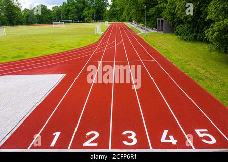 Perspektivische Ansicht eines Freiluftstadions mit rot nummerierten Laufstrecken, Infrastruktur für sportliche Aktivitäten Stockfoto