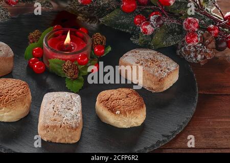 Polvorone und rote dekorative Kerze in der linken oberen Ecke auf einem Schieferteller. Polvoron ist ein typisches Produkt von Weihnachtsgebäck in Spanien Stockfoto