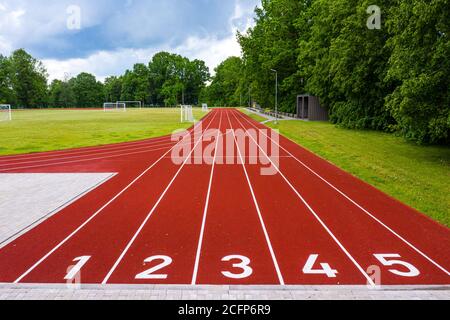 Perspektivische Ansicht eines Freiluftstadions mit rot nummerierten Laufstrecken, Infrastruktur für sportliche Aktivitäten Stockfoto