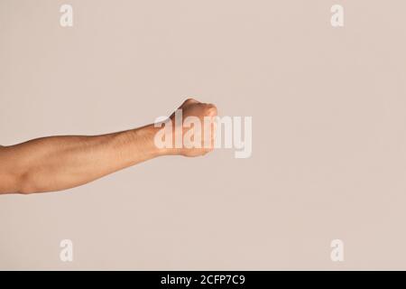 Beschnittene Ansicht des jungen Mannes, der geballte Faust auf Licht zeigt Hintergrund Stockfoto