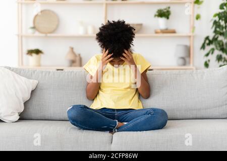 Unglücklich Schwarz Mädchen Berühren Kopf Sitzen Auf Couch Zu Hause Stockfoto