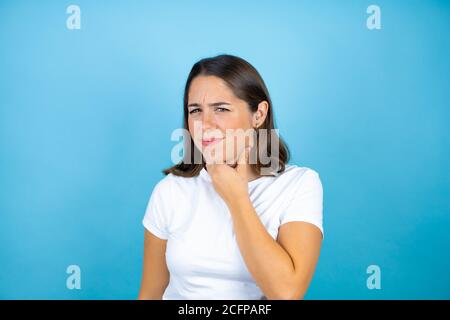 Junge schöne Frau über isolierten blauen Hintergrund berühren schmerzhaften Hals, Halsschmerzen für Grippe, gerötet und Infektion Stockfoto