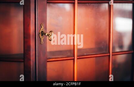 Selektiver Fokus Vintage Gold Farbe Schlüssel auf Holzrahmen Glas Türschaltschrankmöbel Stockfoto